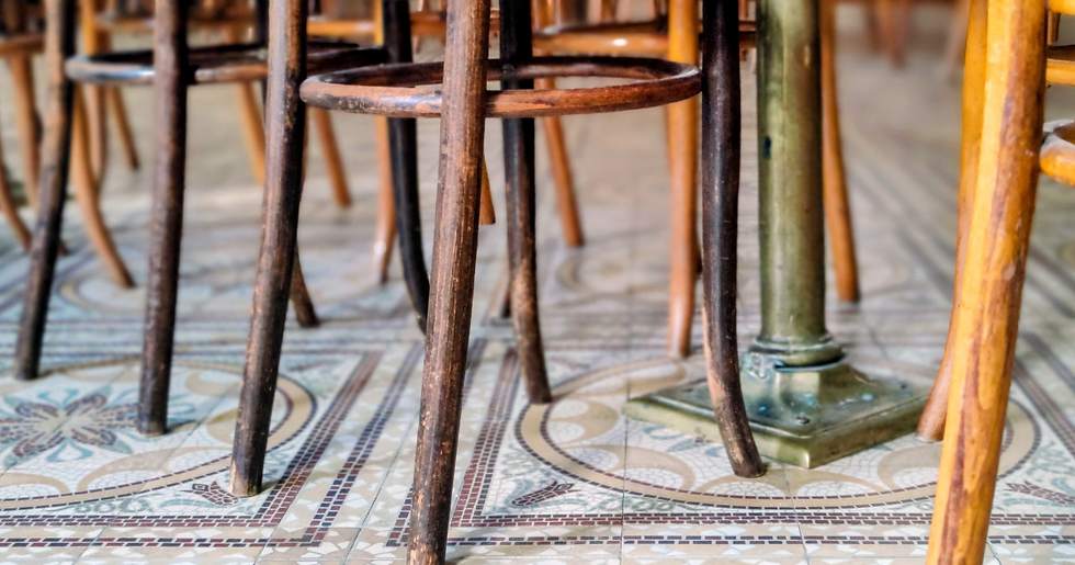 רגלי כיסא מעץ על רצפת אריחים מעוטרת, תקריב. גוונים צהובים וחומים יוצרים אווירה כפרית ונעימה.