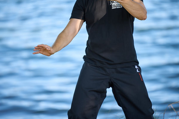 Nahaufnahme einer Person beim Üben der 26er-Kurzform des Taijiquan mit entspannter Körperhaltung und offener Handposition vor