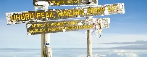 Uhuru Peak Tanzania sign with text, Africa's highest point, snowy background.