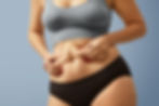 Uma mulher de top segurando as suas gorduras localizadas na barriga