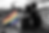 Two young people are sitting on the ground, embracing. A rainbow flag sits nearby. In the background Hiroshima destroyed. Black and white image, except the flag. Dramatic image. Strong contrast between the black and white and the rainbow colors of the flag.