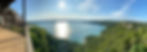 A panoramic view of the Lake Travis surrounded with trees from a view point under cloudy s