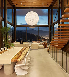 luxury living room with massive windows, custom lighting, and a beautiful wooden staircase