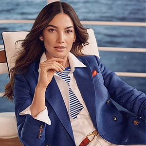 Model sits near the ocean wearing a nautical outfit