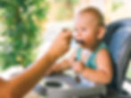Um bebê aprendendo a comer de foma tranquila, durante a introdução alimentar