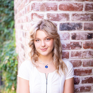 Outdoor senior portrait with a rustic brick backdrop