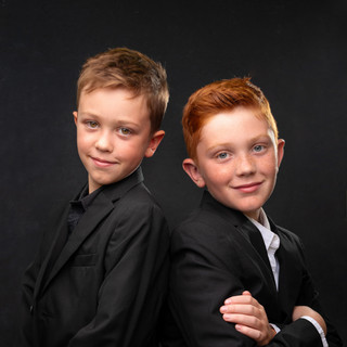 Formal portraits of two young brothers on a dark backdrop in studio in Penn Valley, CA.