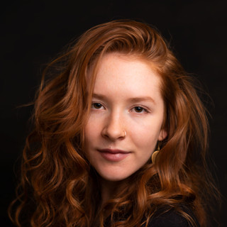 Portrait of a High School Senior with red hair and freckles on a dark backdrop