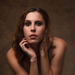 Beauty Portrait of a woman in gold with glamorous makeup and curly hair in studio in Penn Valley, CA.