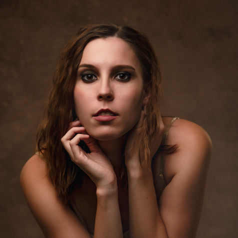 Beauty Portrait of a woman in gold with glamorous makeup and curly hair in studio in Penn Valley, CA.