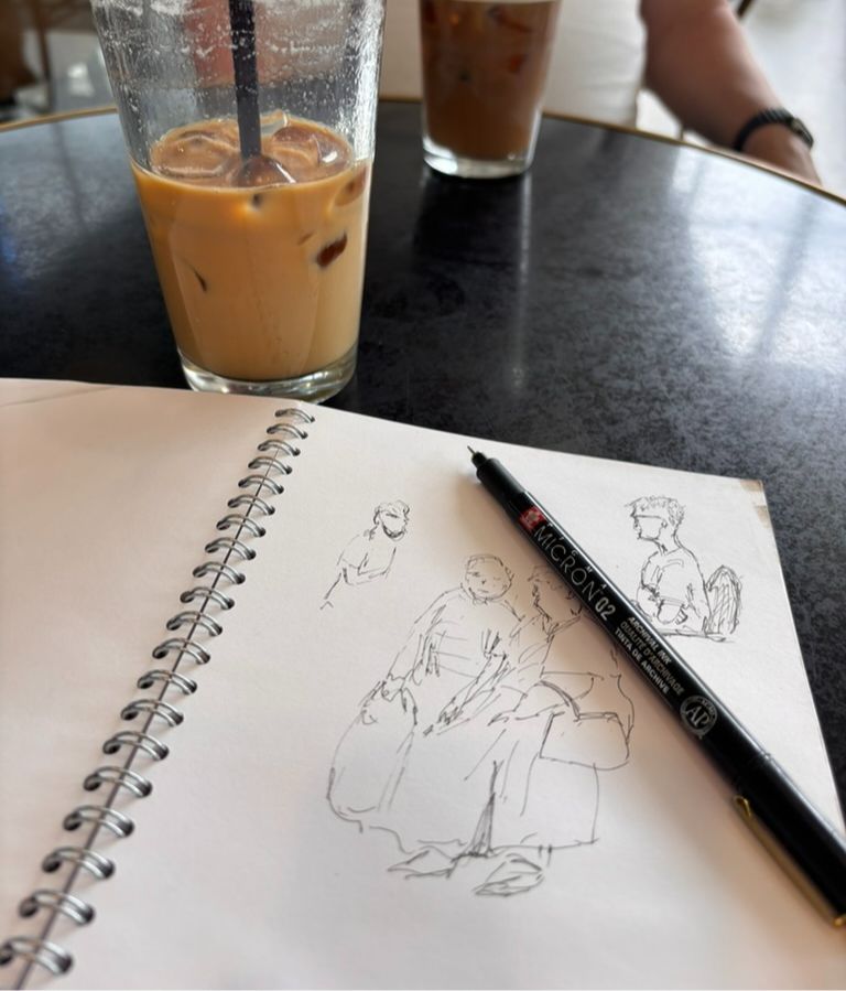 Coffee and a sketchbook with line drawings of people