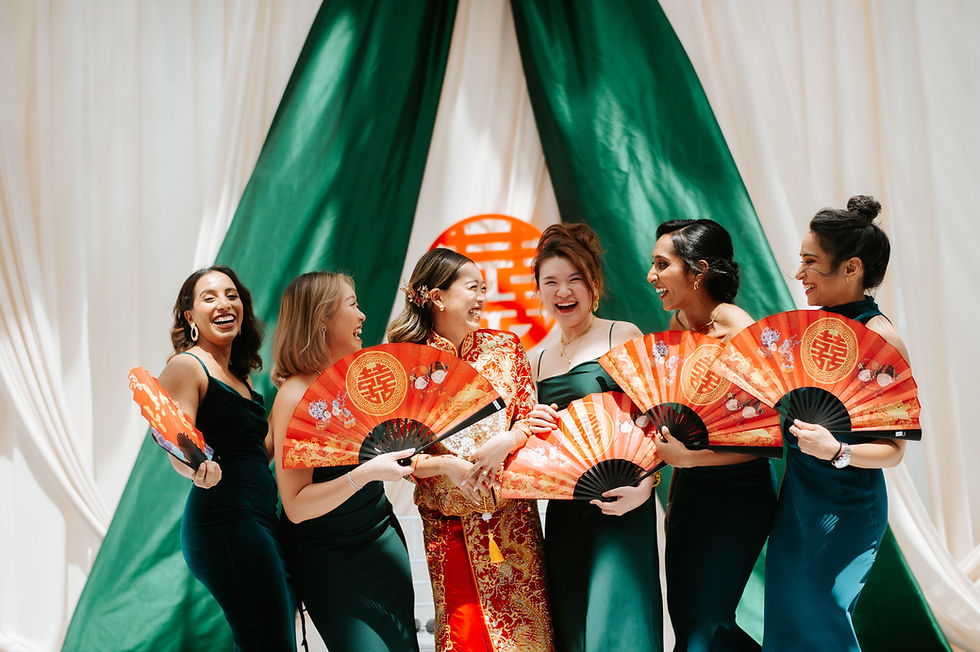 Bride in a traditional red Chinese wedding outfit celebrates with friends holding red fans.