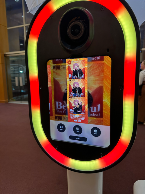 Rainbow LED oval mirror booth displaying the touchscreen photo booth interface at an event