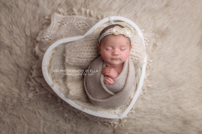 Newborn girl wearing floral bonnet during studio photoshoot