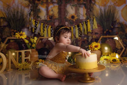 Baby having fun with a birthday cake during a colourful cake smash and splash photography session
