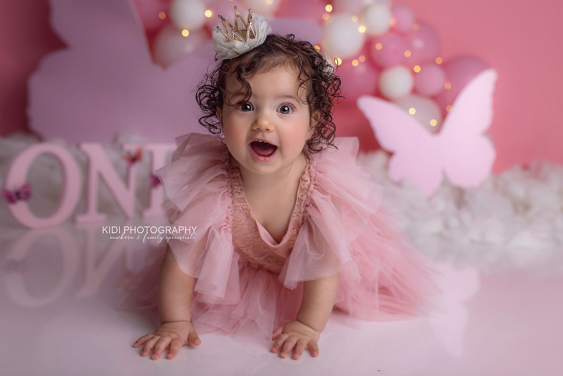 Cake smash photoshoot Wolverhampton featuring baby girl in a soft pink setup, celebrating first birthday with elegant styling