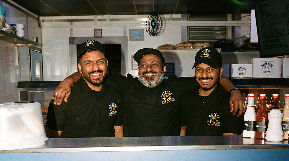 Three smiling men in uniform behind a counter