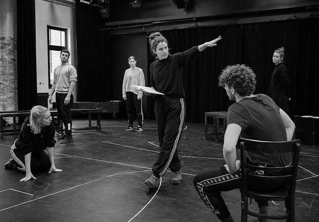 Physical theatre ensemble creating stage pictures and choreographed movement composition in rehearsal space