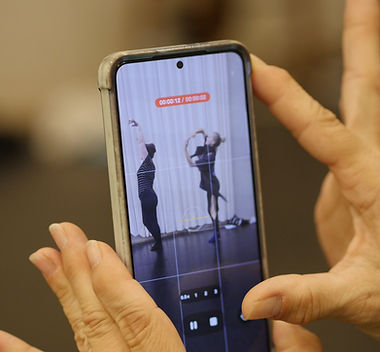 A participant films two dancers on a phone during a NIPAI session