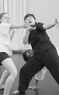 Performers engaged in expressive physical theatre improvisation, exploring gesture, rhythm, and partner interaction in a studio workshop.