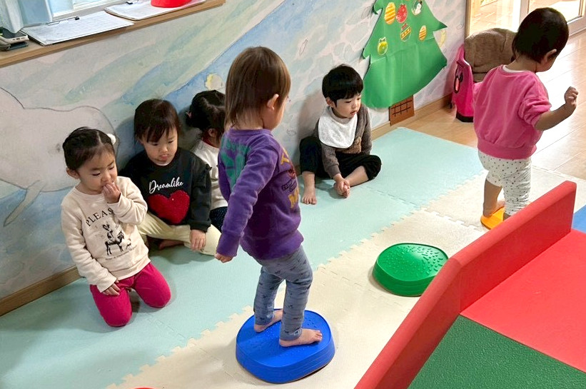 バランス遊びをする子供と見守る先生
