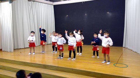 園児たちがステージで手を挙げています。7月【年長】盆踊り練習、みんなで練習しています。