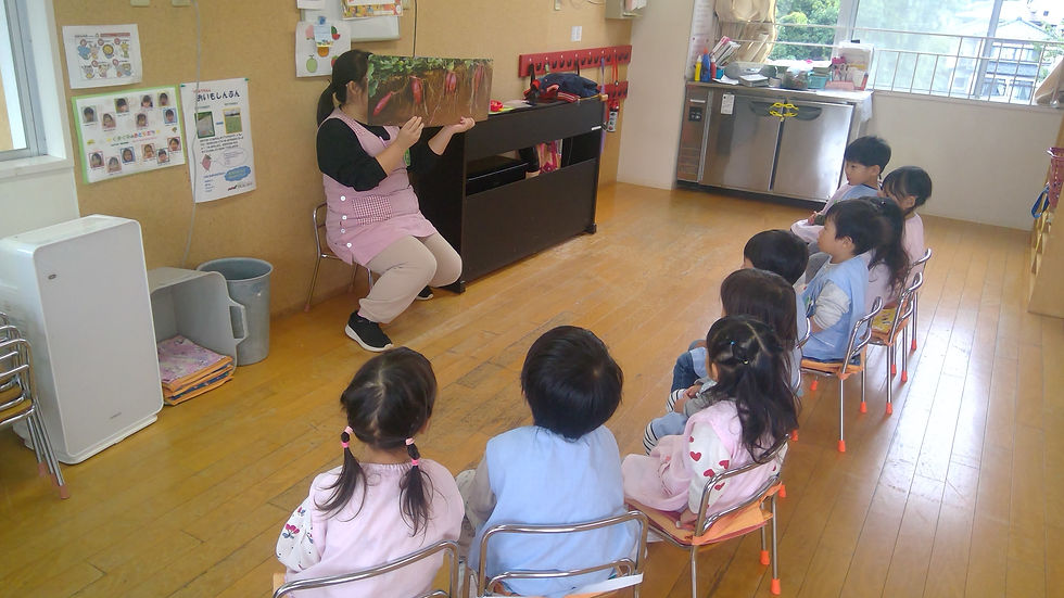 先生が子供達に絵本を読んでいる様子 園の生活 幼稚園の教室で読み聞かせ