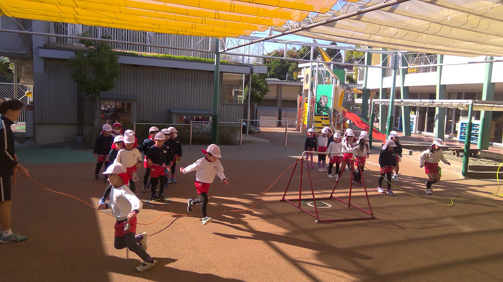 園庭で遊ぶ子供たち。先生が見守り、楽しそうな姿。子供たちは元気よく遊んでいます。