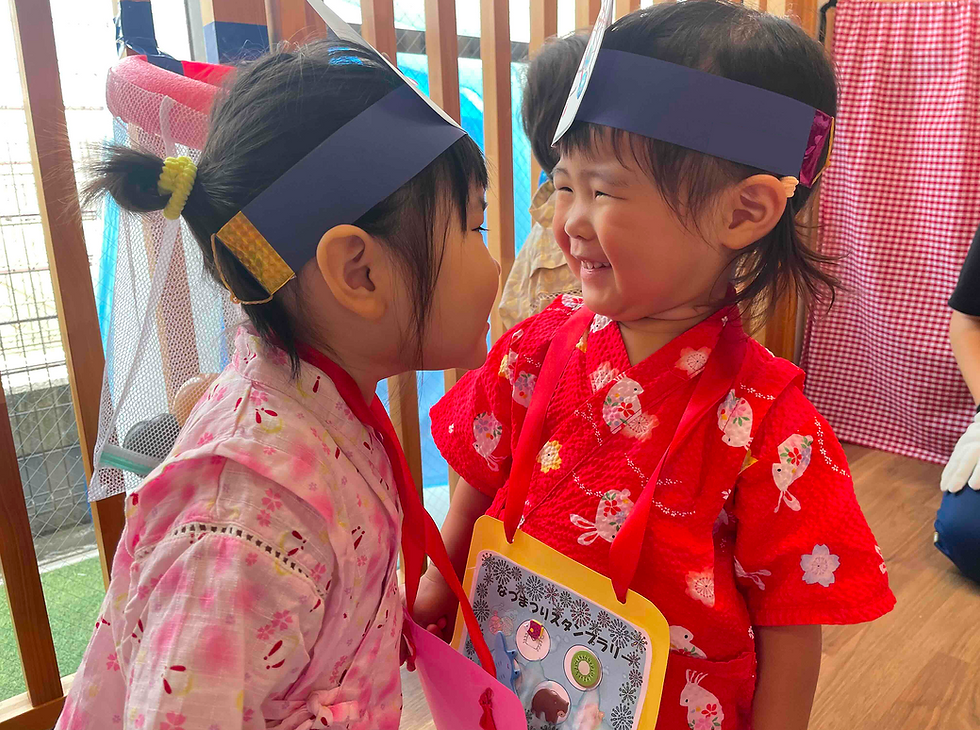 二人の女の子が笑いながら遊んでいます。ピンクと赤の浴衣、マジオブルームキッズ。