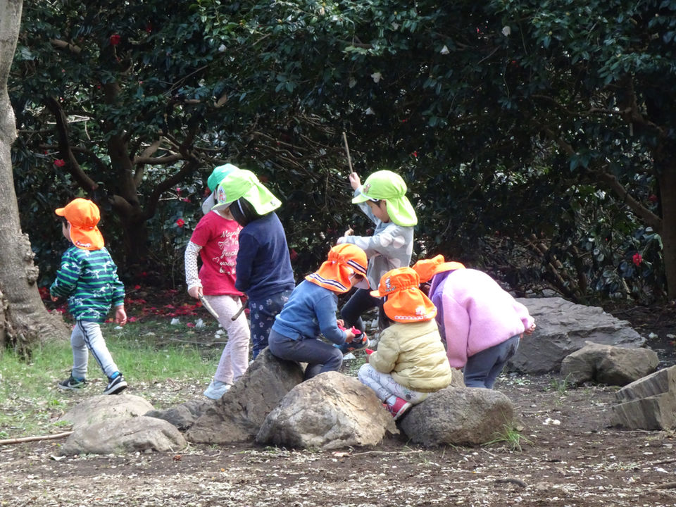 公園の石に座って遊ぶ子供たち