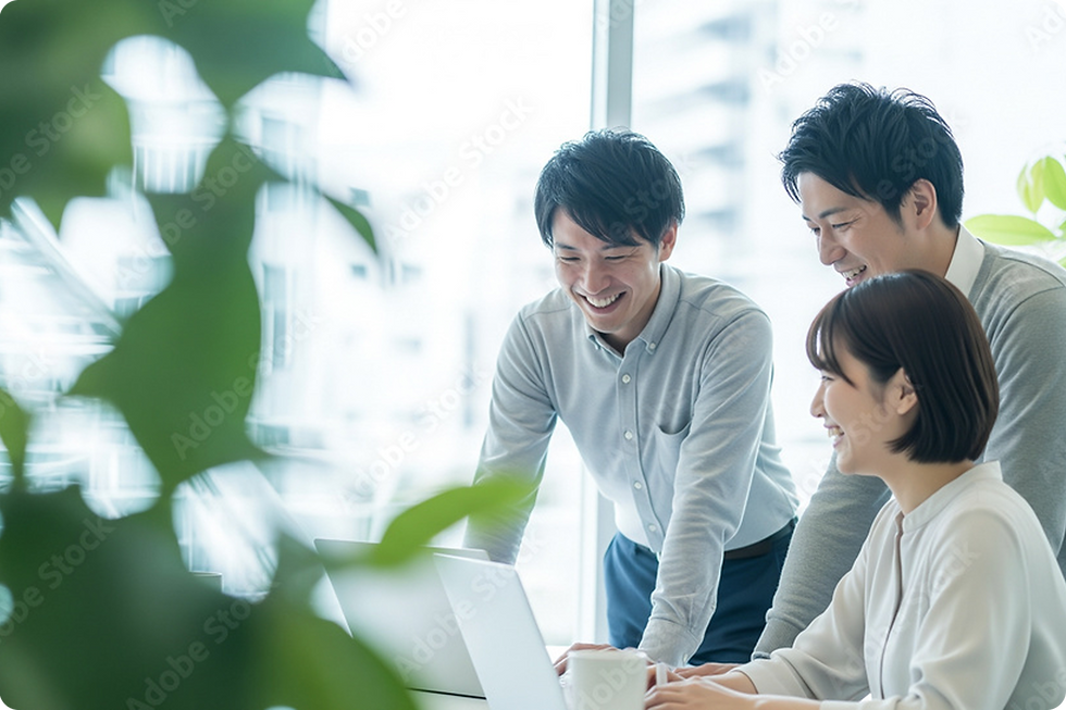ノートパソコンを見て笑顔で協力する3人。