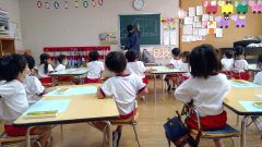 先生が黒板に字を書く様子、生徒たちは授業中 7月【年少】大掃除を行う教室