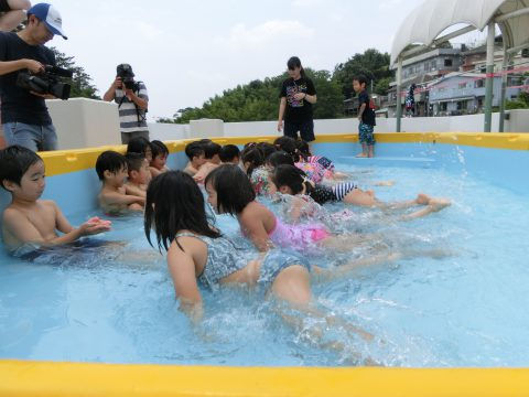 水遊びする子供たち。先生とカメラマンもいる。年長組　遠足【こども宇宙科学館】夏休みの思い出。