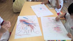 子供たちがクレヨンで絵を描いています。1月【年少々】節分製作、カラフルな作品がテーブルに並んでいます。