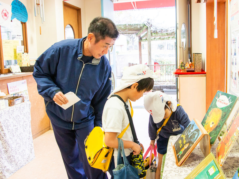 男性と2人の子供が絵本を見ている
