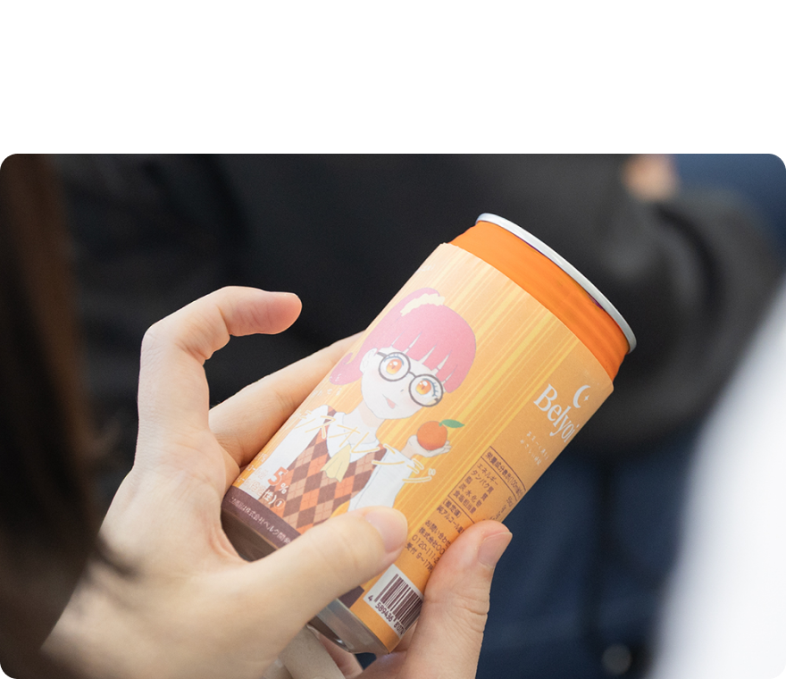 手で持った、アニメの女の子が描かれた飲み物の缶