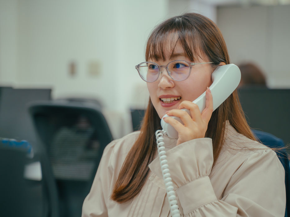 笑顔の女性社員が電話応対中