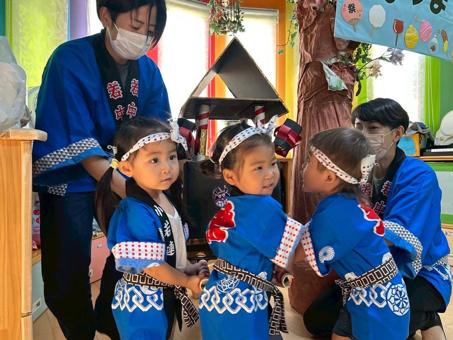 青い法被を着て綱を持つ子供たちと大人