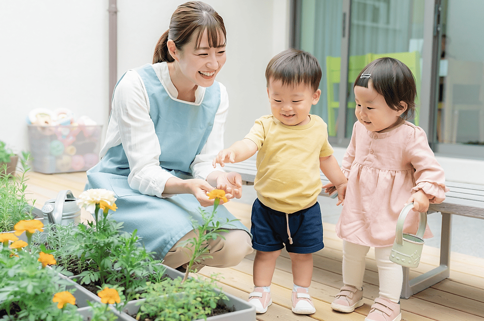 保育士と子供たちが庭で花を観察する
