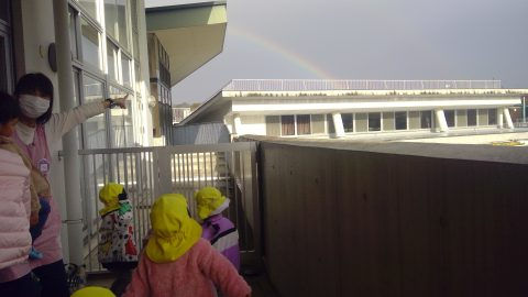 保育士と園児が虹を指差す、7月【年少々】今週の様子。バルコニーで虹を見上げる様子。