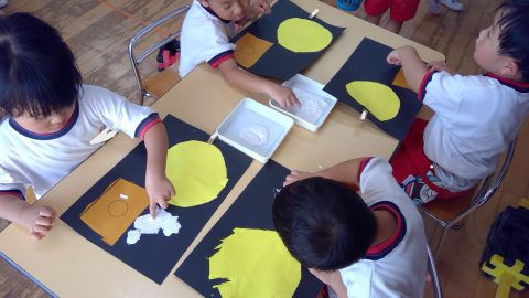 子供たちが工作で黄色い月を制作しています。白い紙と黒い台紙、5月【年少々】今週の様子。