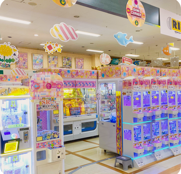 明るいゲームセンター、クレーンゲーム「CRANE GAMES」「SR」が並ぶ店内。
