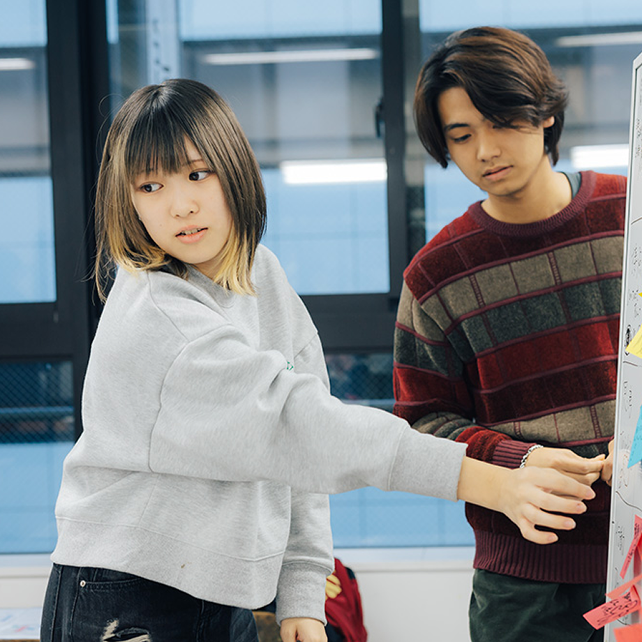 若い男女がボードを指し、話し合っている