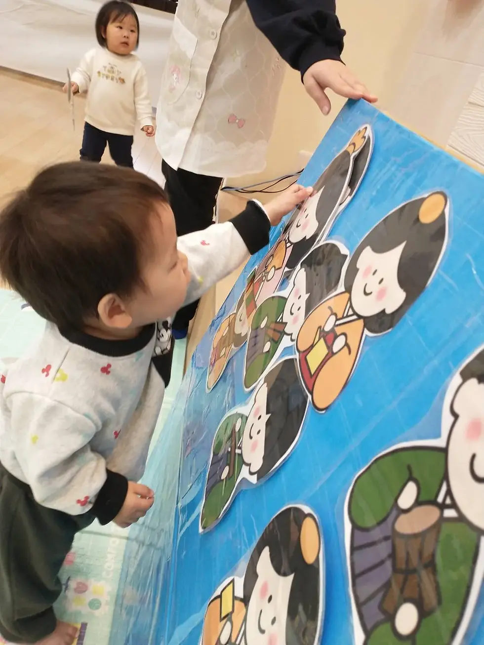 青いボードのキャラクターに触れる子供