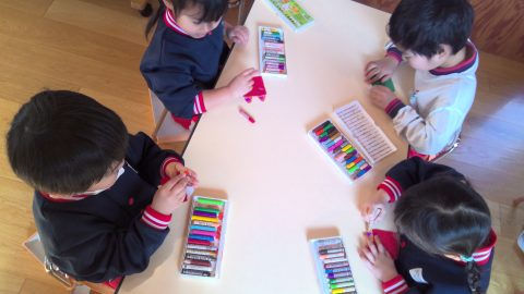幼児がクレヨンを使って絵を描いています、10月【年少】園外遠足、机の上で集中しています。