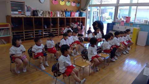 椅子に座る子供たち、白いシャツ、赤いパンツ。１０月【年中】今週の様子、幼稚園の教室。