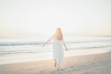 太陽に向かって浜辺を歩く女性