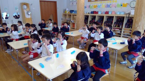 教室で歯磨きをする子供たち。7月【年中】走り方教室。机に座り、健康的な習慣を学ぶ様子。