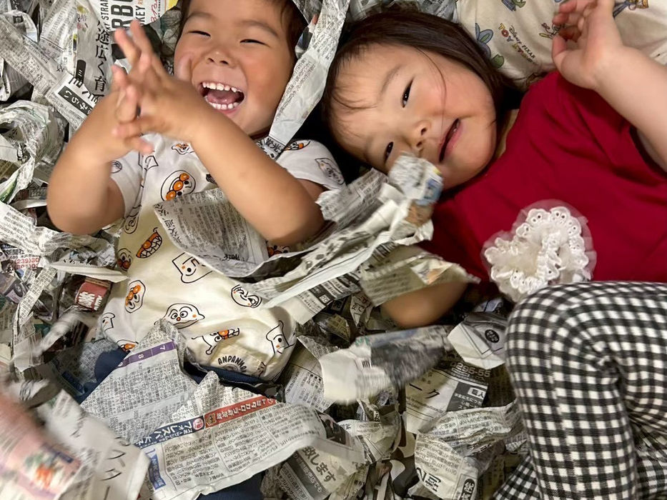 笑顔で紙くずの中で遊ぶ二人の子供