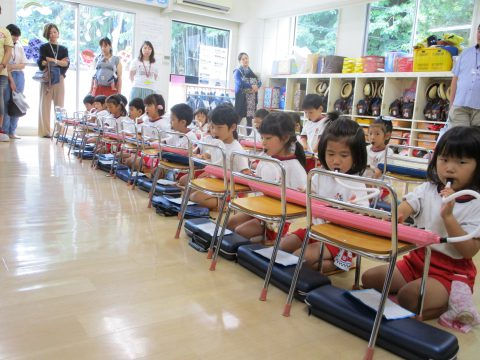 園児たちが鍵盤ハーモニカを演奏、保護者が見守る様子。年長組 参観日、日本の幼稚園。